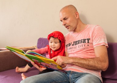 Man leest kind voor op de bank